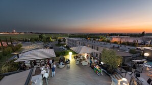 An outdoor event space with seating and tables, surrounded by buildings and a parking area. -  DB HOTEL VERONA, AIRPORT CONGRESS & SPA (Sommacampagna)