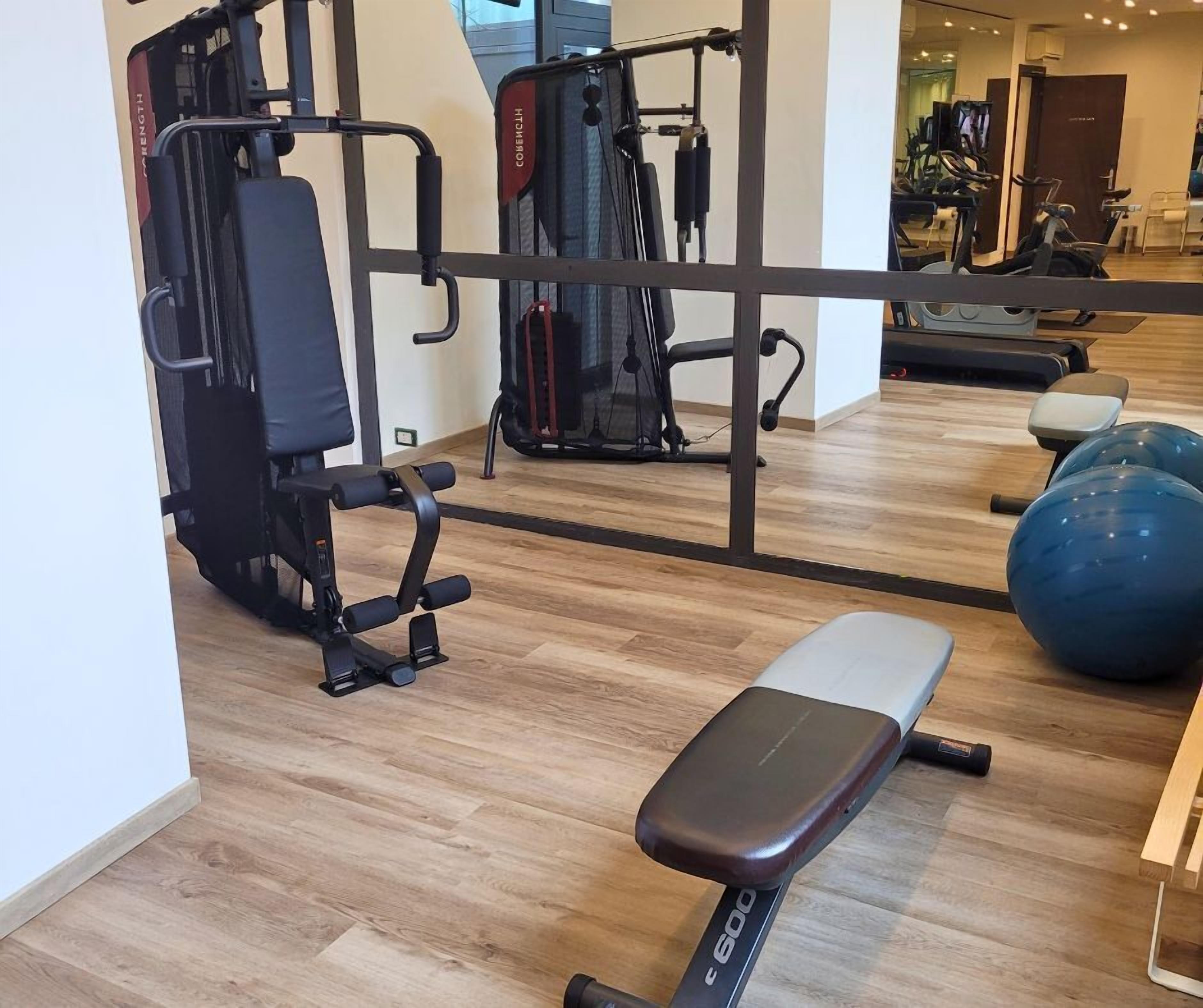 Een sportschool met trainingsapparatuur, een bank en een grote fitnessbal.