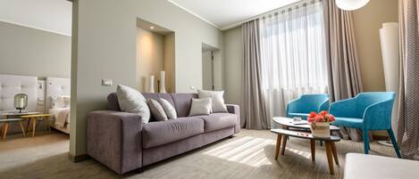 A modern living room with a sofa, a coffee table with flowers, and a blue chair.
