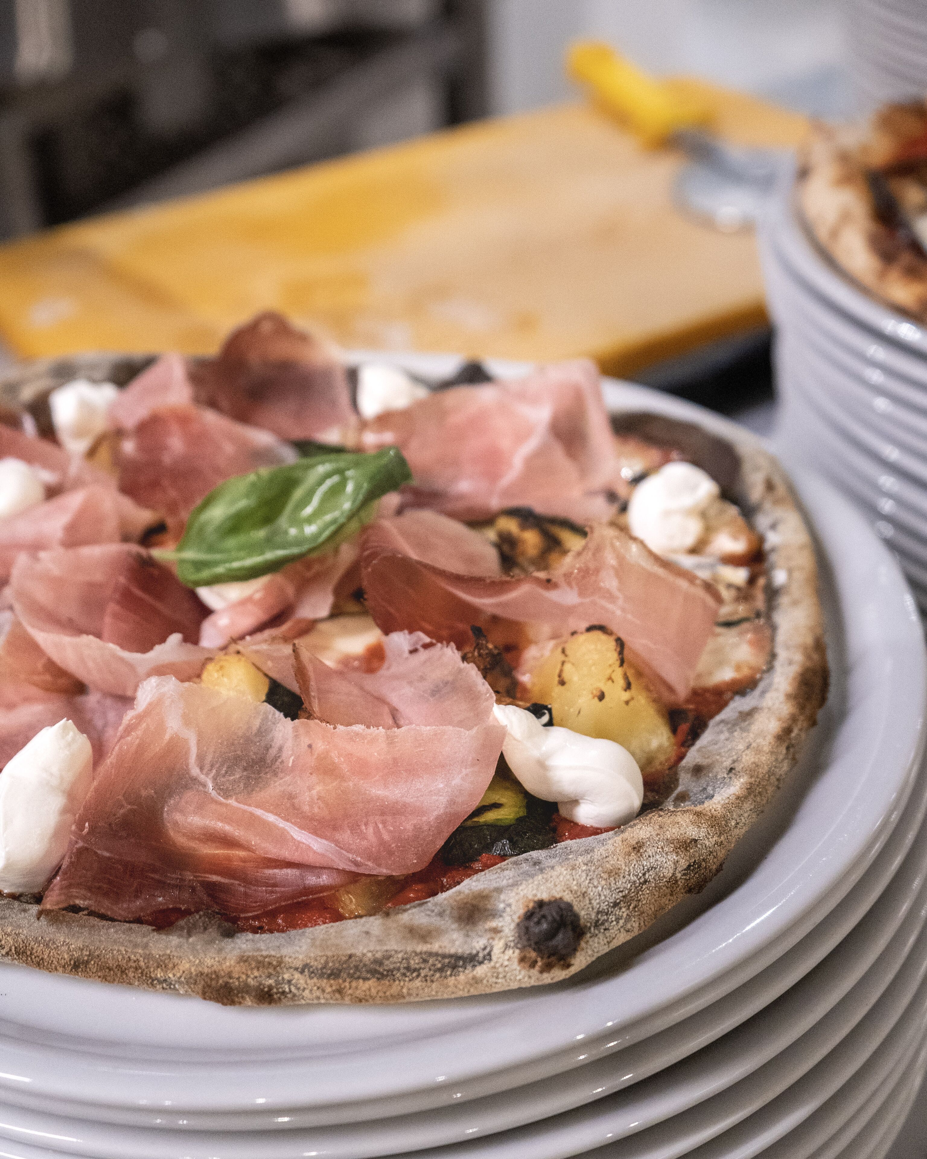 Eine Pizza mit Prosciutto und Käse auf einem Teller.
