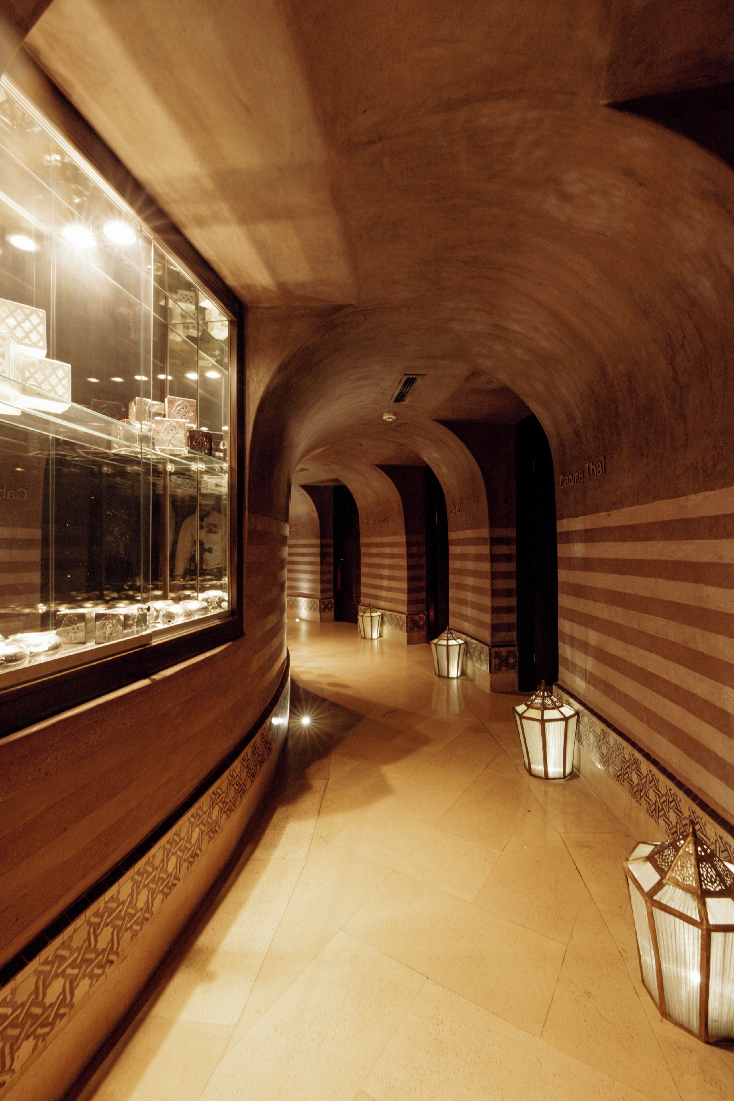 A corridor with arched ceilings, a glass display case, and patterned walls.