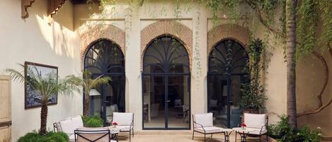 Un patio con tres ventanas de arco, una fuente y asientos al aire libre.