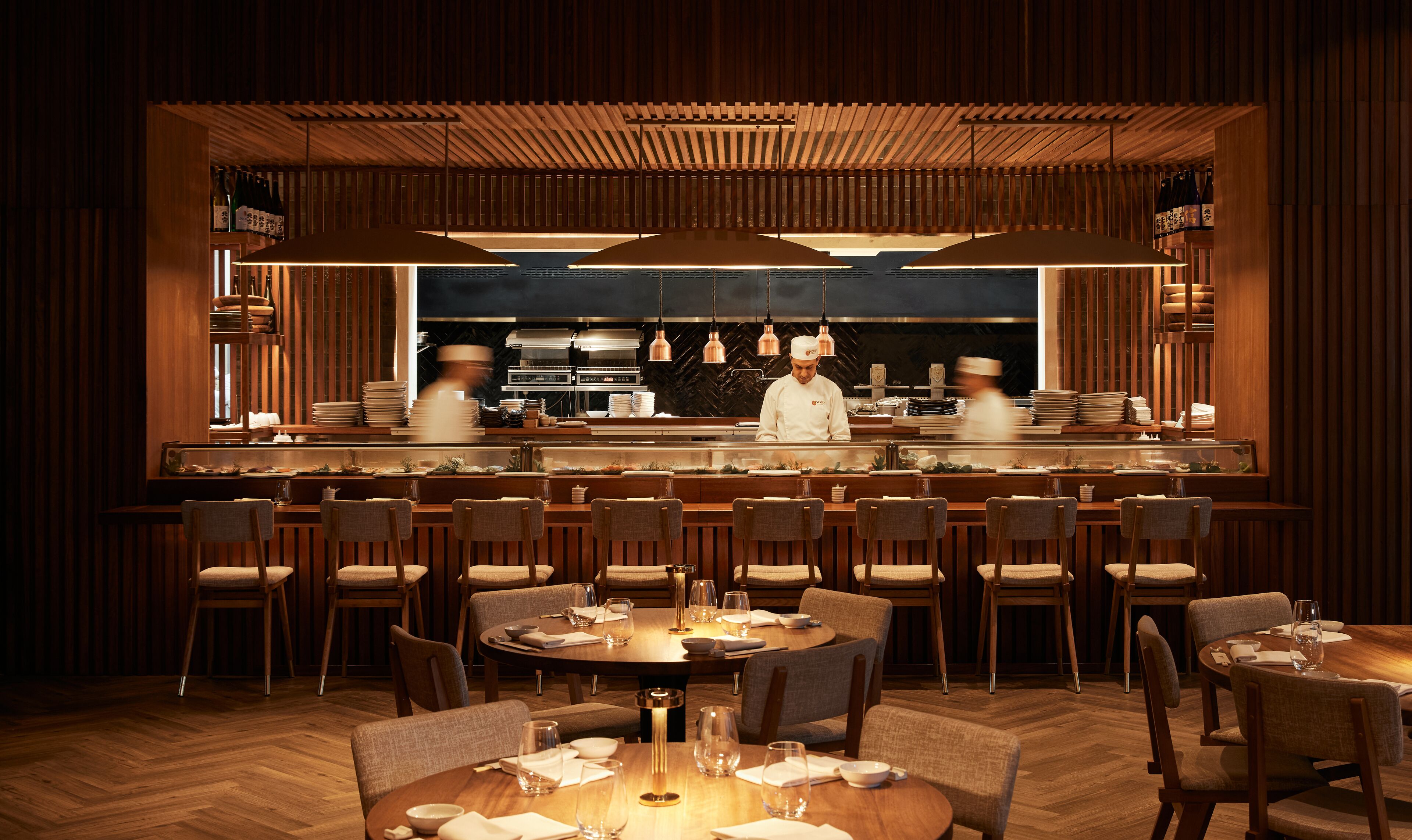 A restaurant with a wooden interior, multiple dining tables, and chairs.