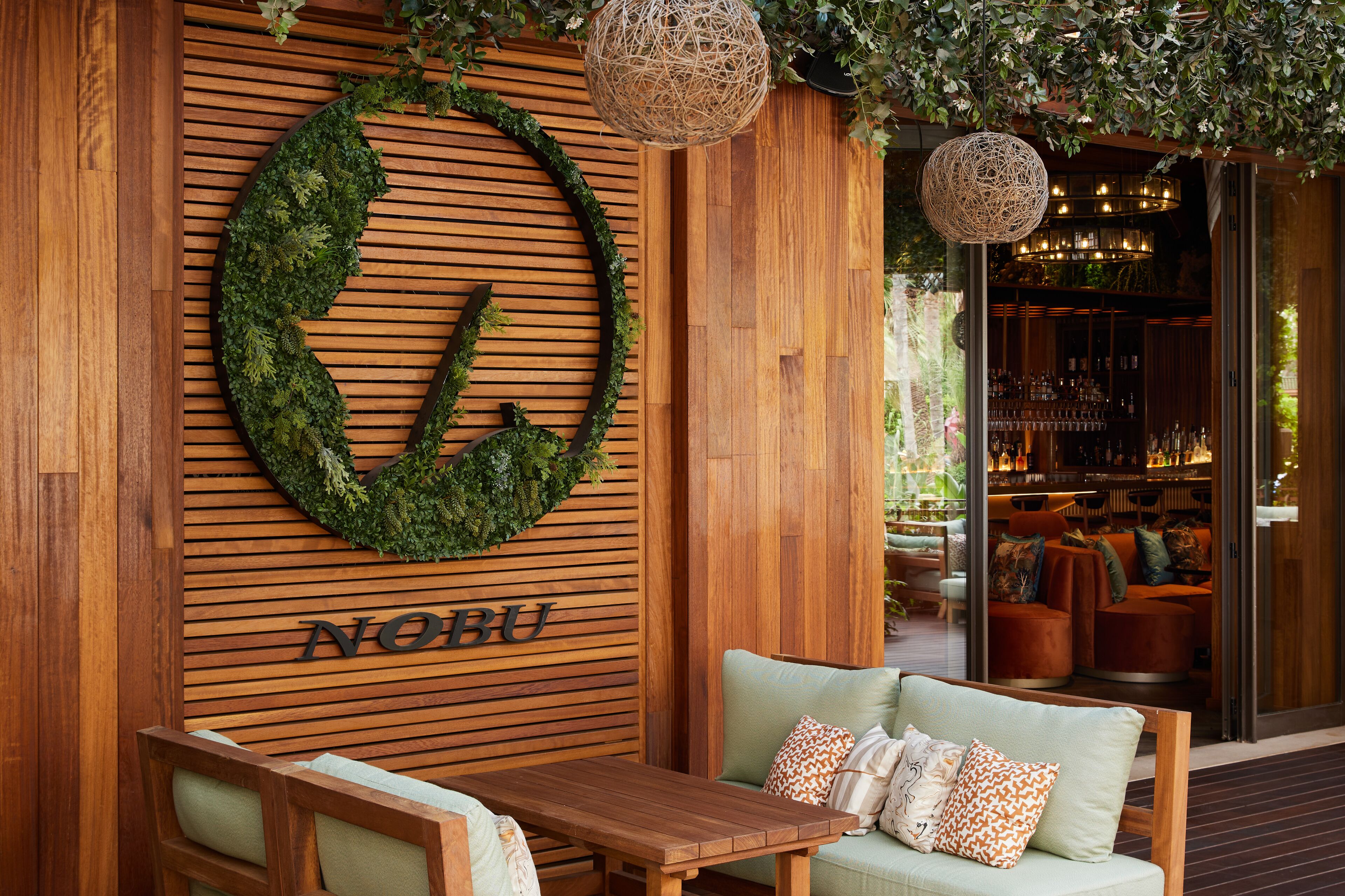 Un mur en bois orné d’un motif circulaire vert, avec les lettres « NOBU » en dessous.