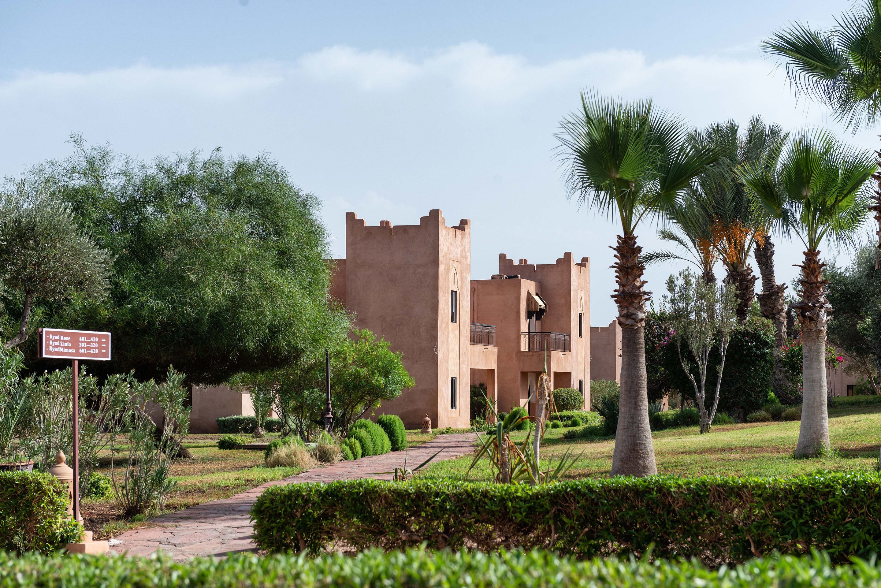 A building with a traditional architectural style, surrounded by well-maintained greenery and palm trees.