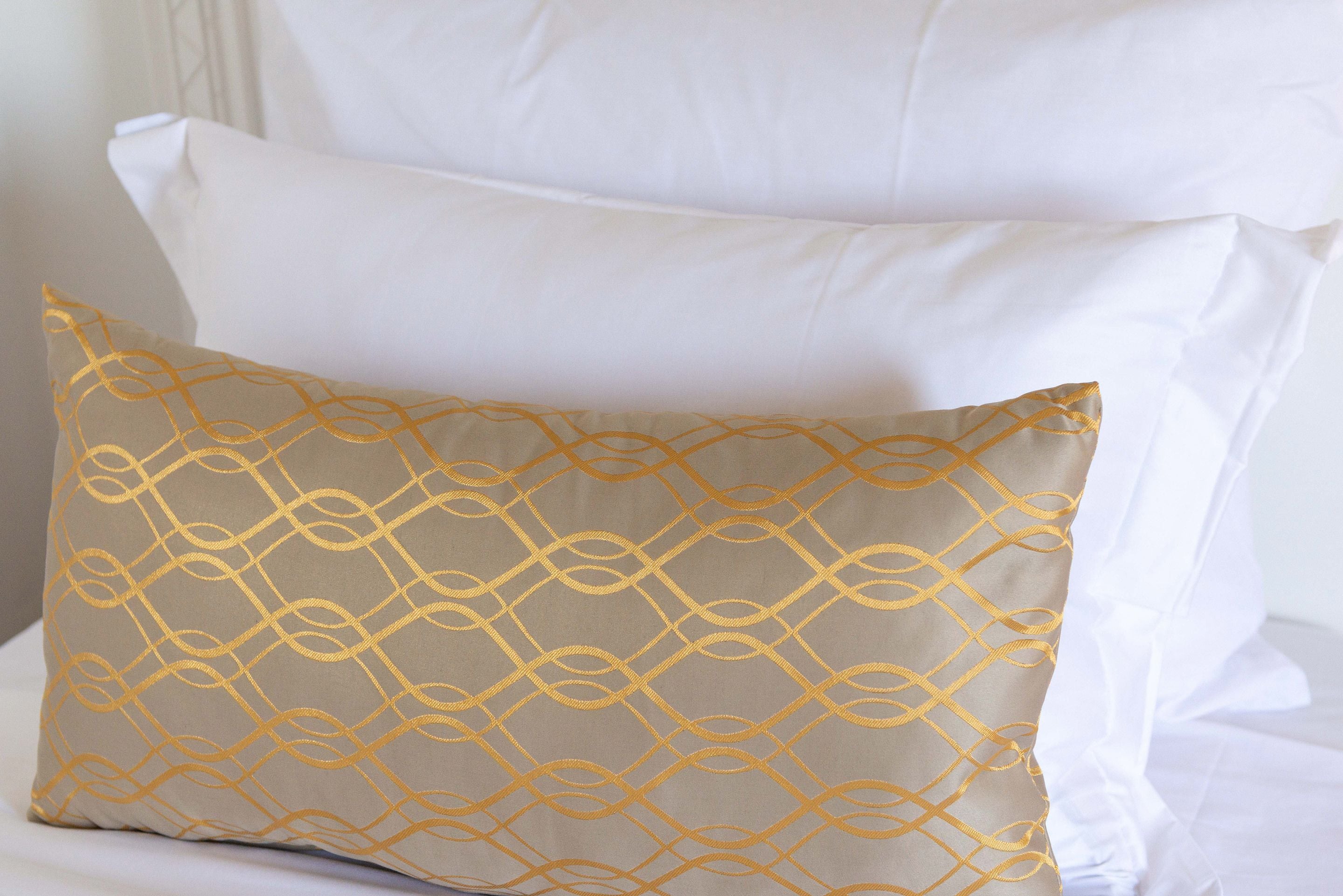 A bed with white and beige pillows, one with a geometric pattern.