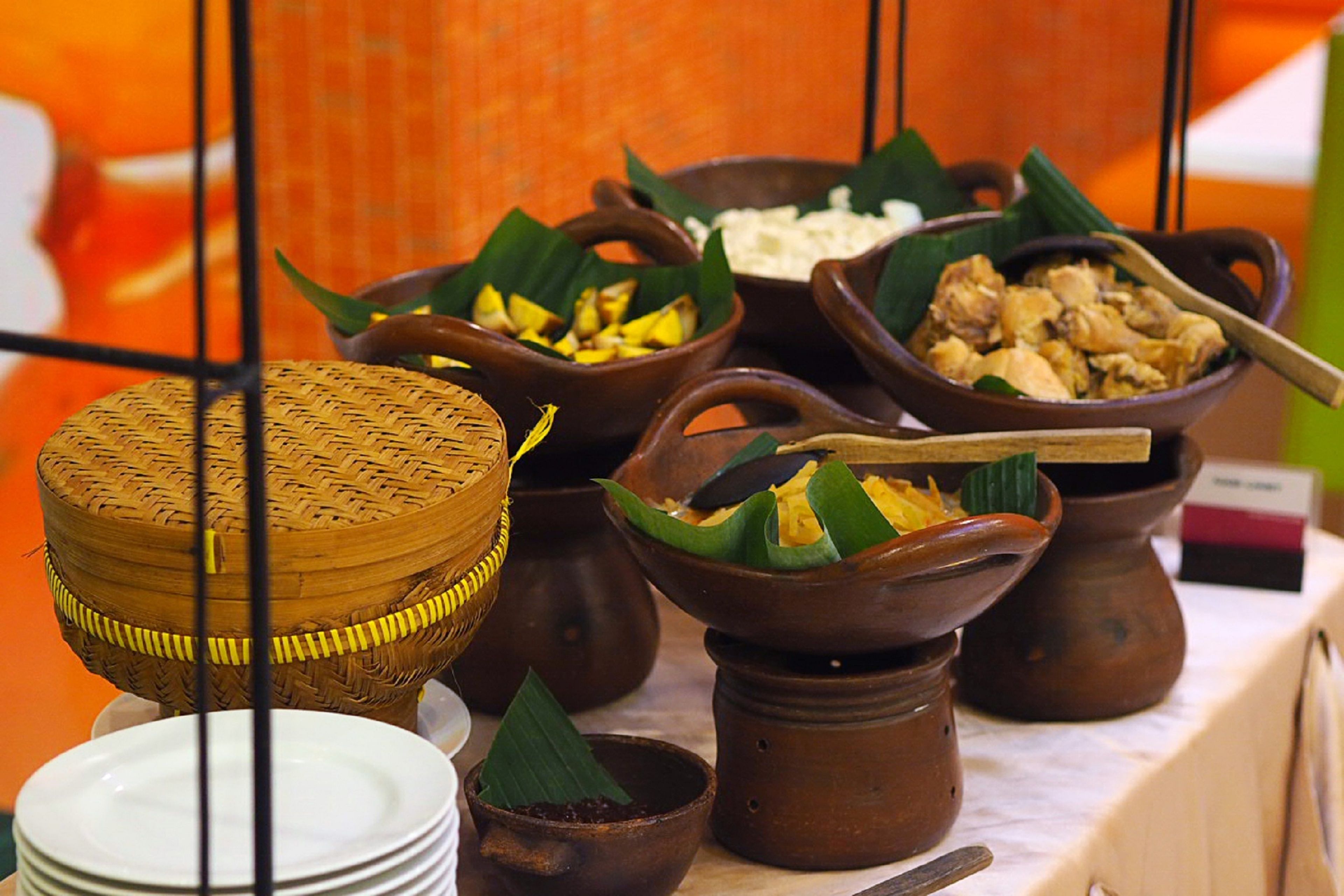 A display of traditional food items in various ceramic and woven containers.