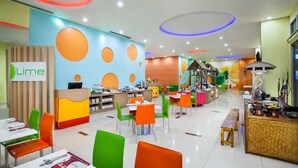Un restaurant lumineux, avec des chaises et des tables aux couleurs vives, un comptoir sur lequel est affiché un panneau indiquant « Lime », et un espace de jeux en arrière-plan.