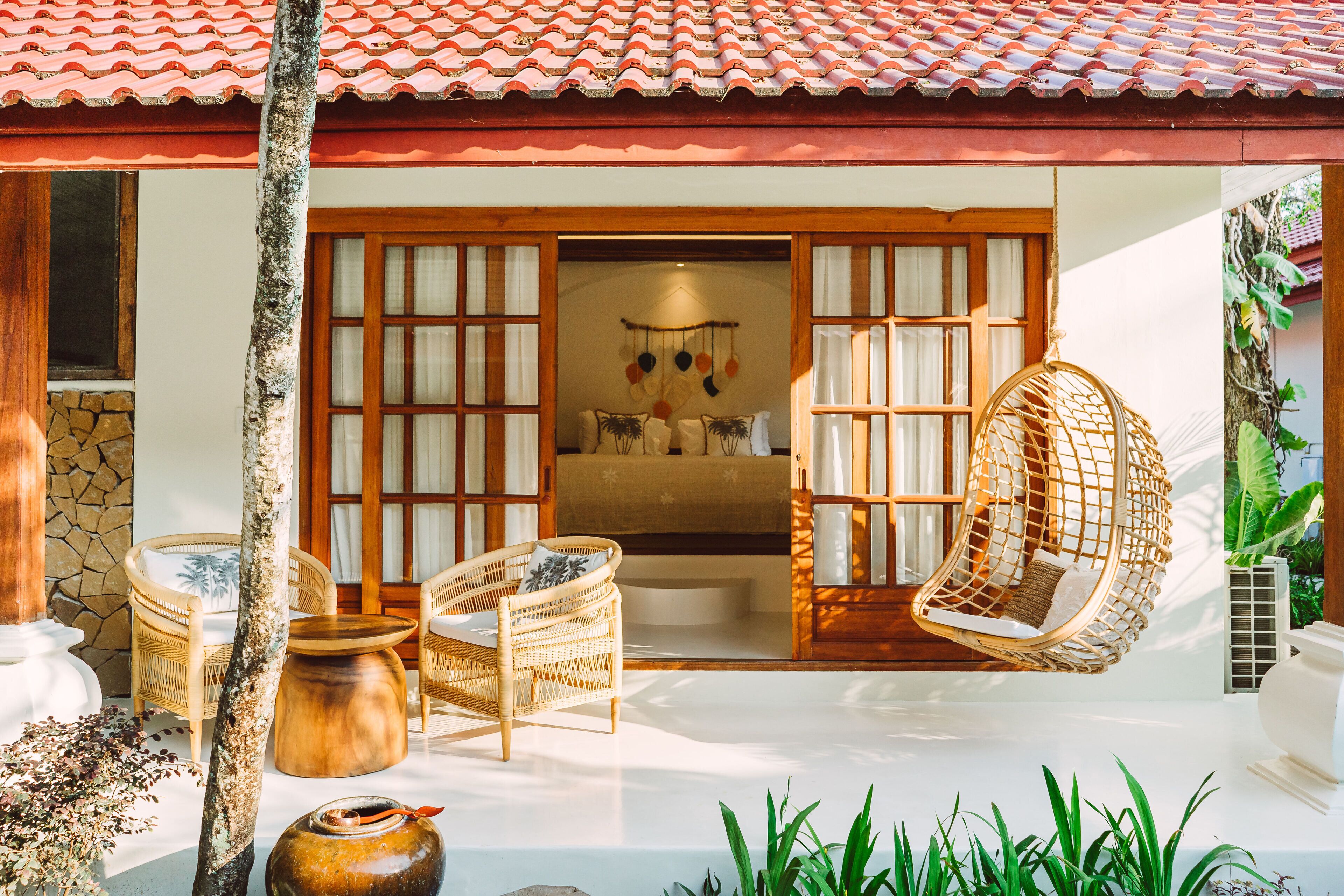 A traditional-style room with wicker furniture, a stone wall, and a tiled roof.