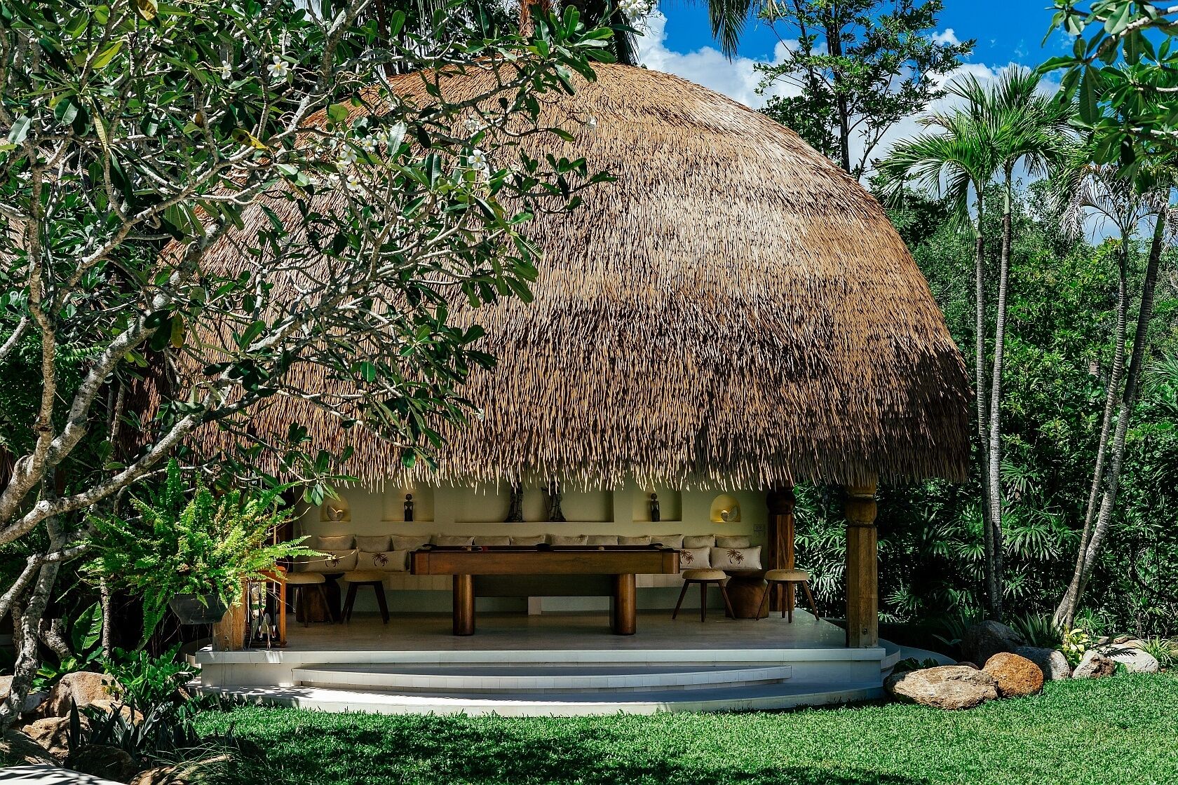 A thatched-roof structure with a seating area and a small pool.