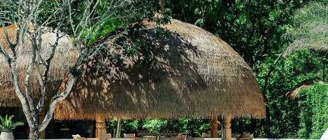 A pool area with thatched umbrellas and lounge chairs.