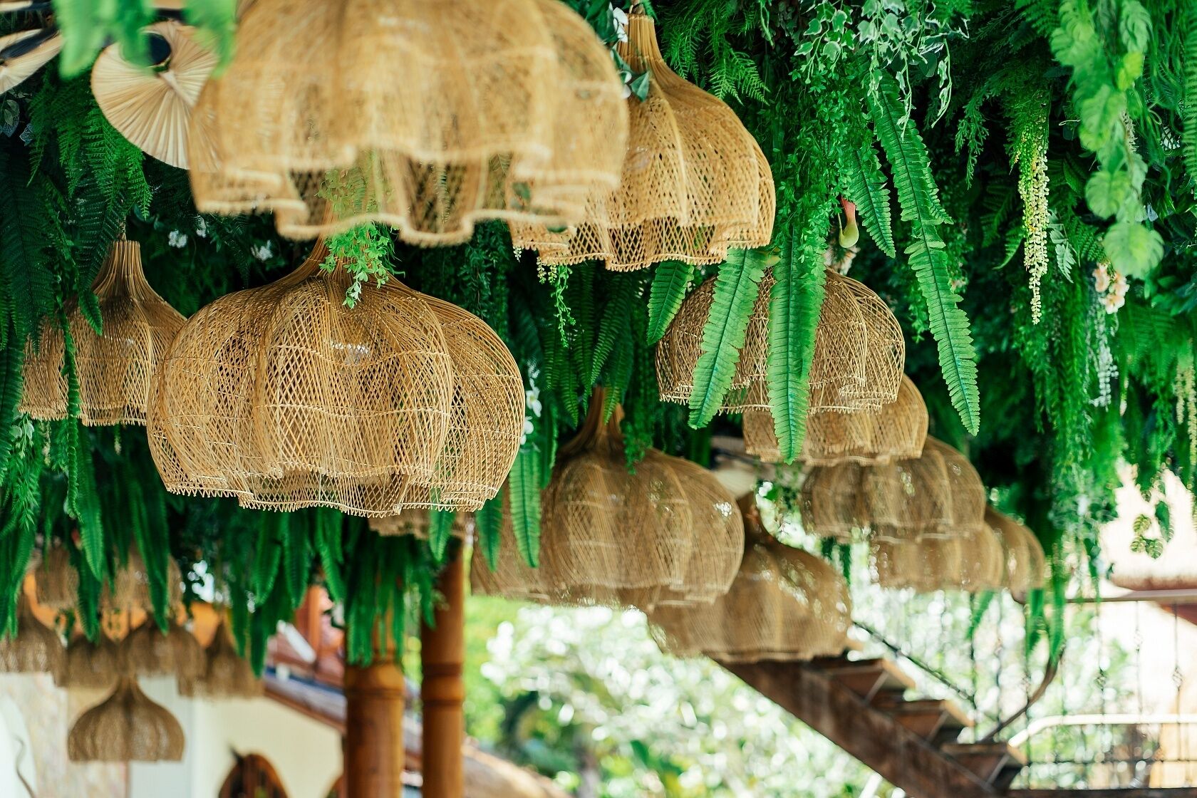 A series of woven hanging lamps and green foliage in a natural setting.