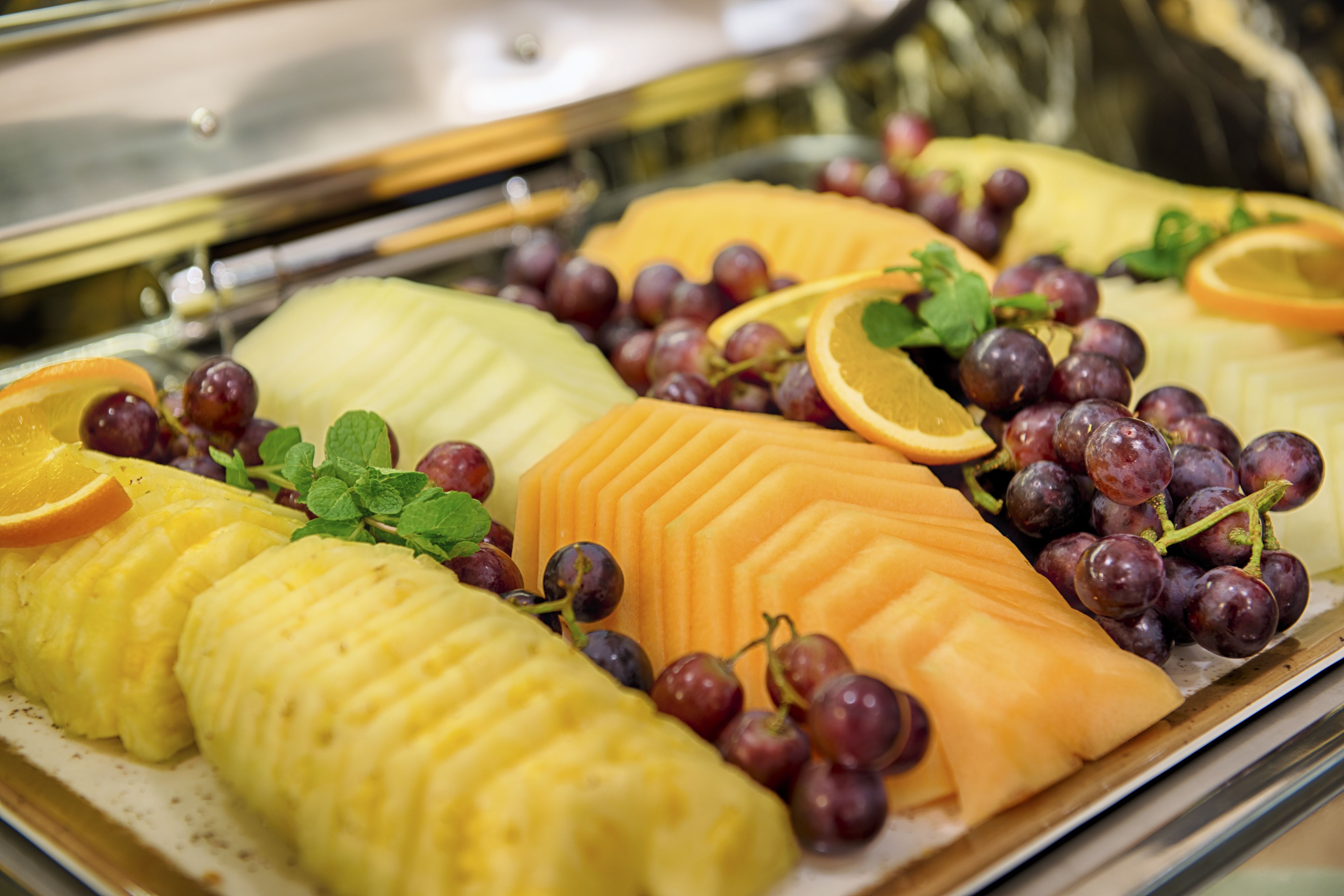A buffet with various fruits and grapes.