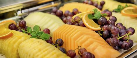 A buffet with various fruits and grapes.