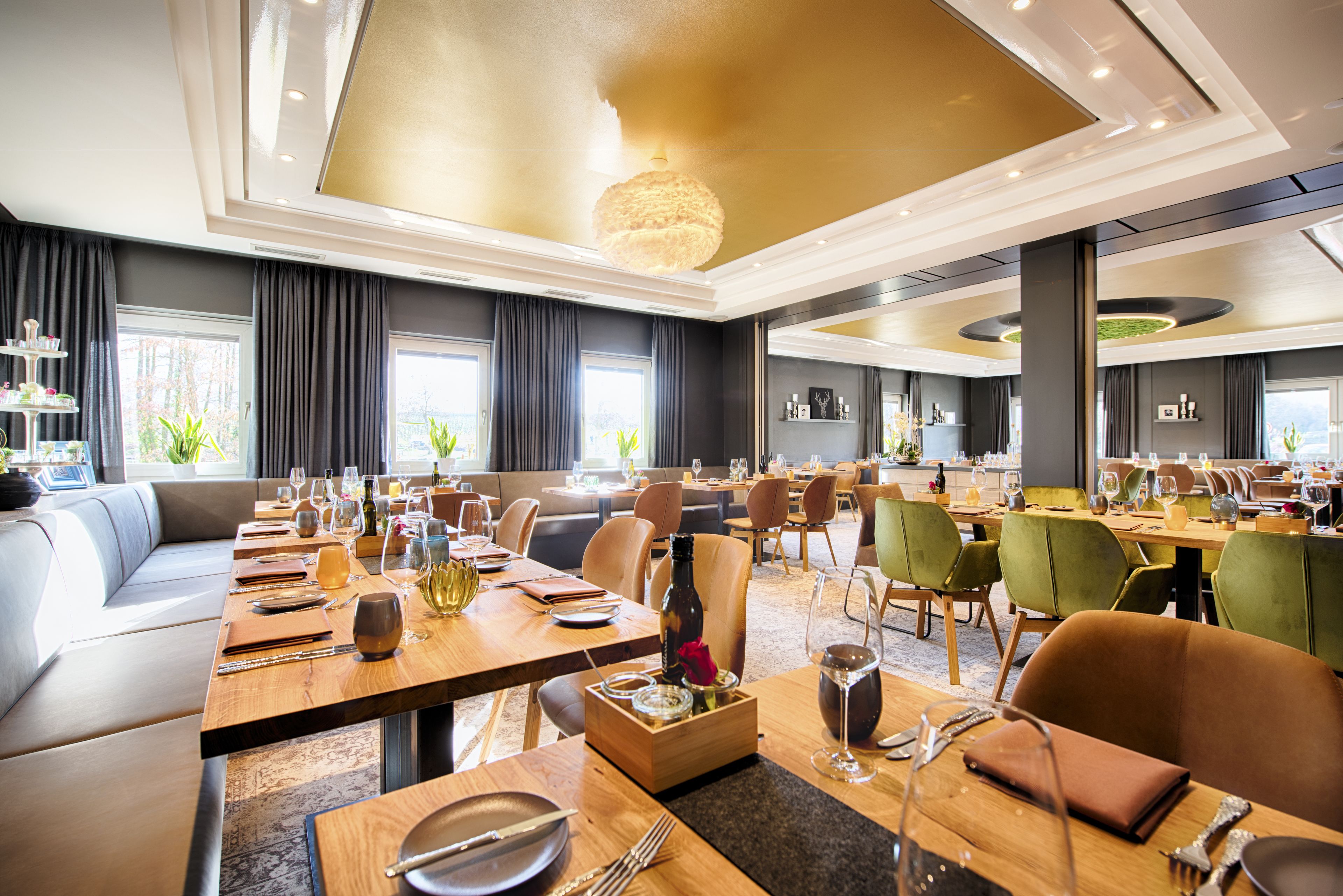 A spacious hotel dining area with multiple tables, chairs, and a large chandelier.