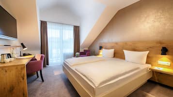 A hotel room with a large bed, a desk with a chair, a television, and a window with curtains.