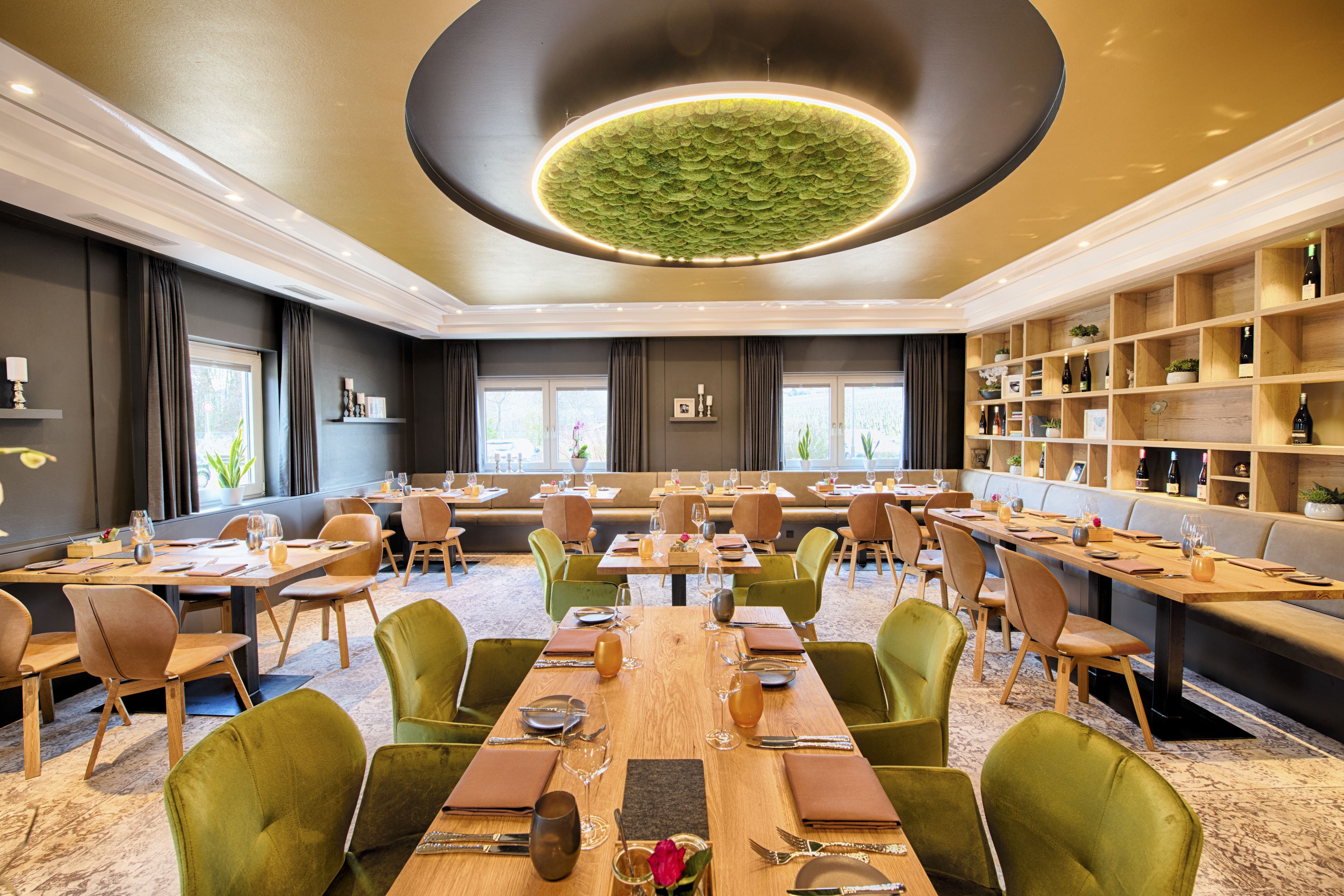 A spacious dining area with multiple tables and chairs, a central chandelier, and a wine display.