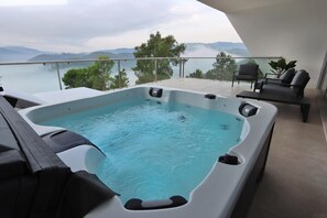 Un jacuzzi en un balcón con vistas a montañas y árboles.