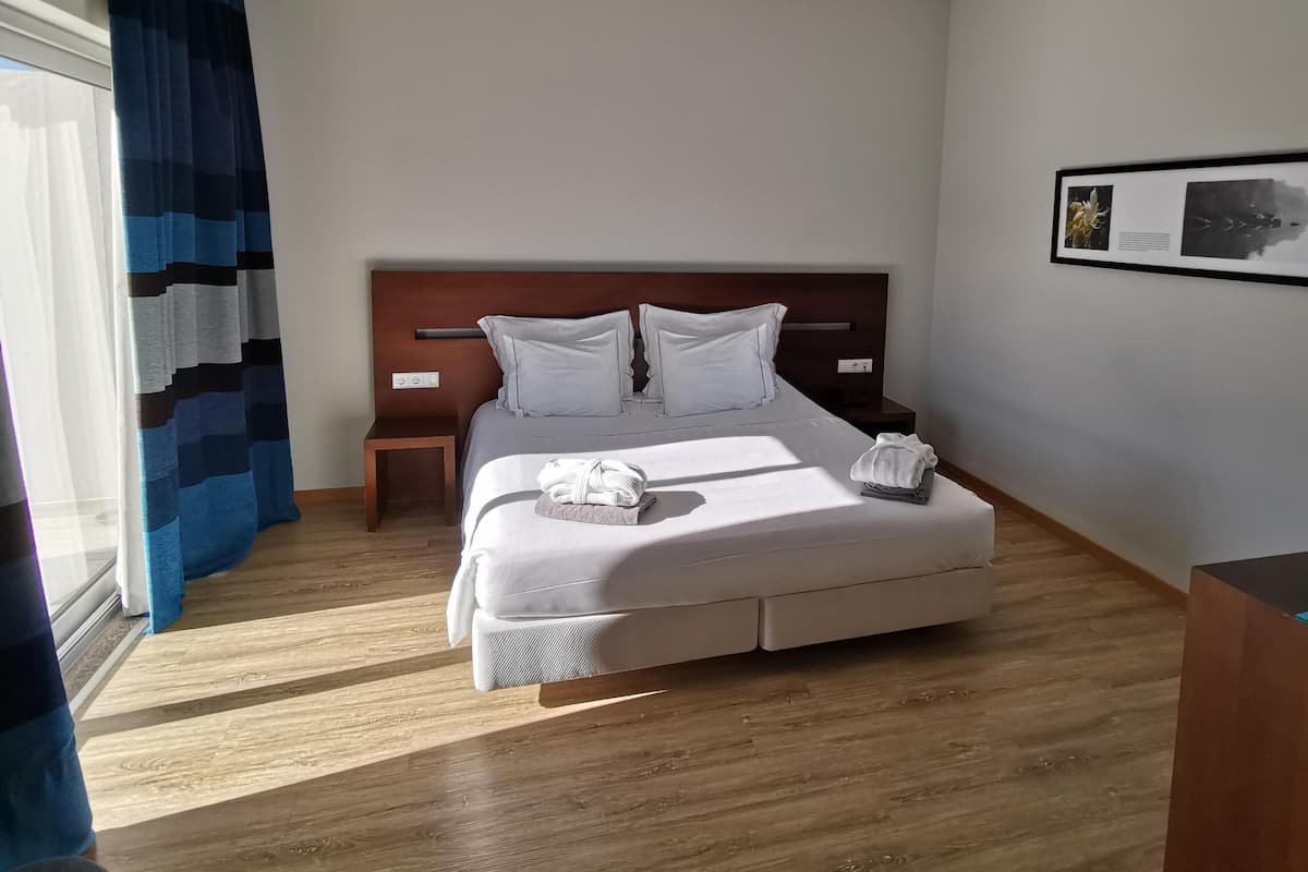 Ett hotellrum med en stor säng, en sänggavel i trä, två sängbord och en inramad tavla på väggen.