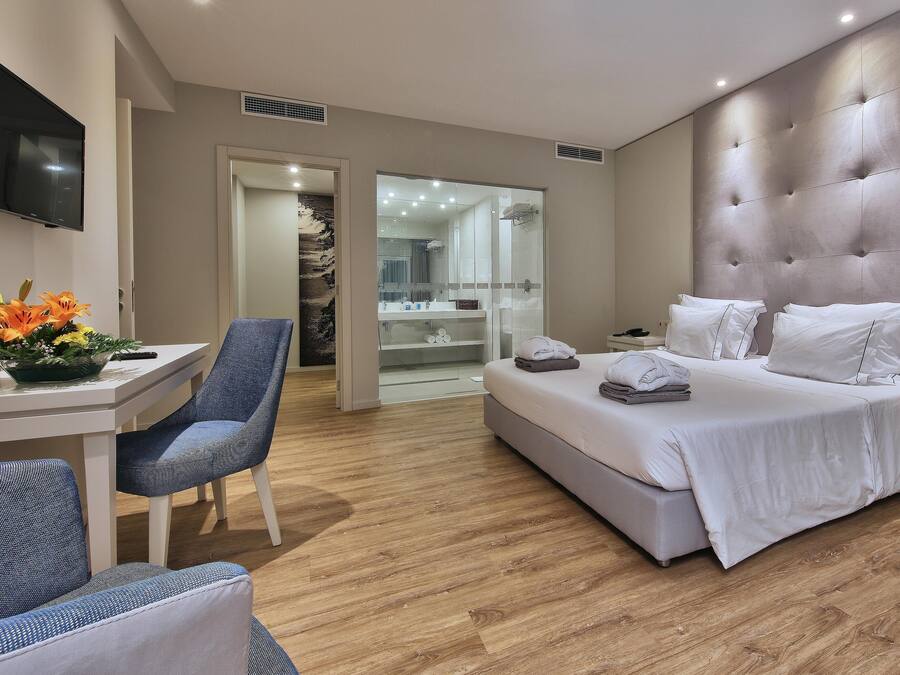 Quarto de hotel moderno com uma cama grande, uma mesa e uma cadeira.