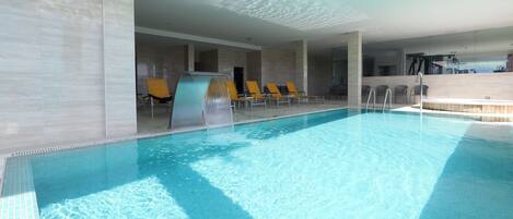 Una piscina con agua cristalina, rodeada de sillas de descanso y un diseño interior moderno.