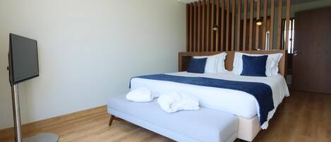 A modern hotel room with a large bed, a flat-screen TV, and a wooden partition wall.