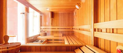 A wooden sauna with benches and a bench seat, wooden walls, and a window.