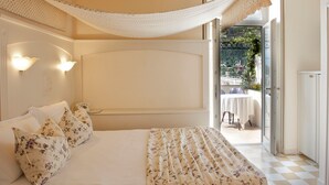 A bedroom with a bed, floral pillows, a canopy, and a view of an outdoor patio. - Bellavista Lakefront (Riva del Garda)