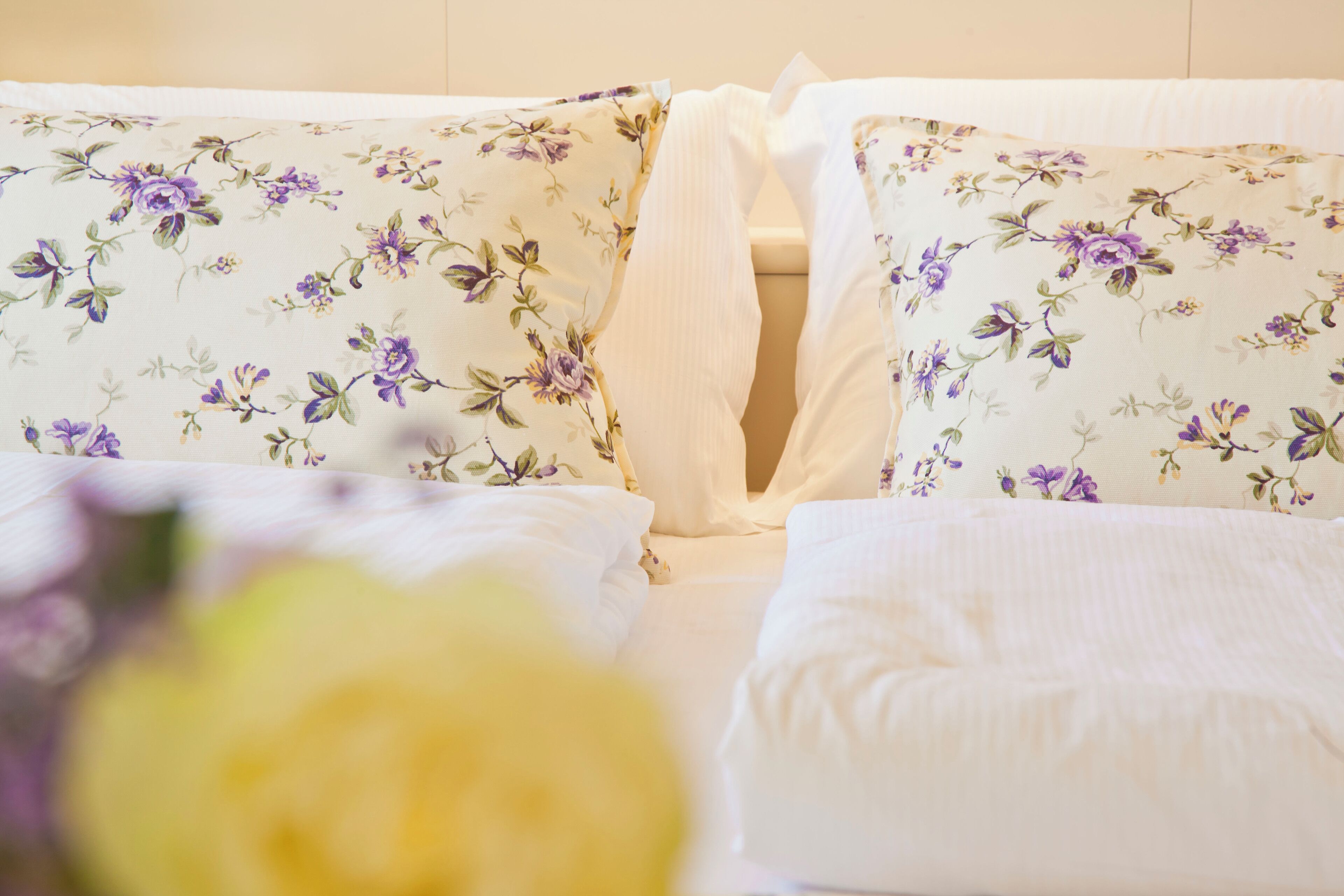Una cama con ropa de cama de estampado floral y una almohada blanca.