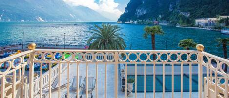 A balcony with a view of a lake, palm trees, and mountains.