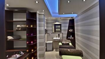 Relax in a serene spa room with a central bench, shelves stocked with spa essentials, and a convenient sink.