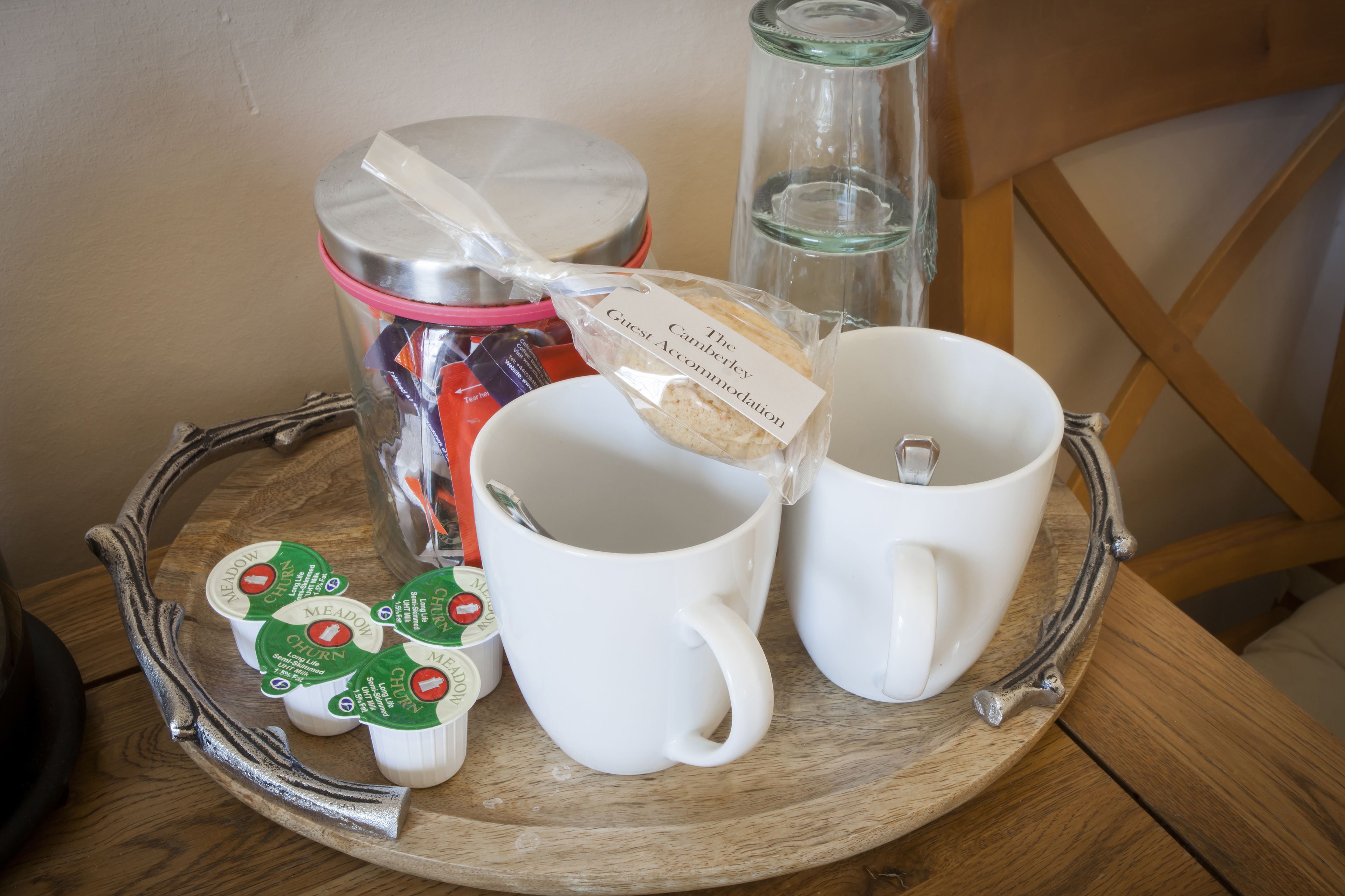 A tray with two white mugs, a glass jar, and packaged food items.
