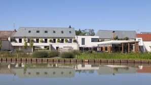 A modern building with a flat roof, large windows, and a reflection in the water.