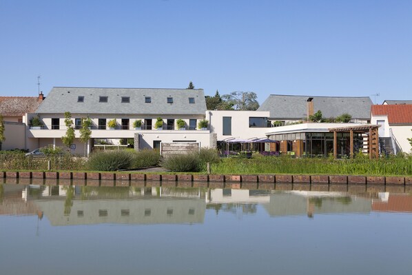 A modern building with a flat roof, large windows, and a reflection in the water.