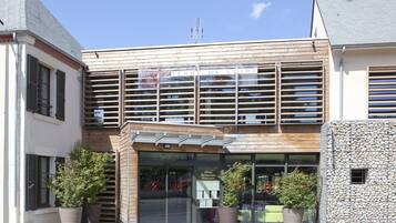 A hotel with a modern facade, large windows, and potted plants in front.