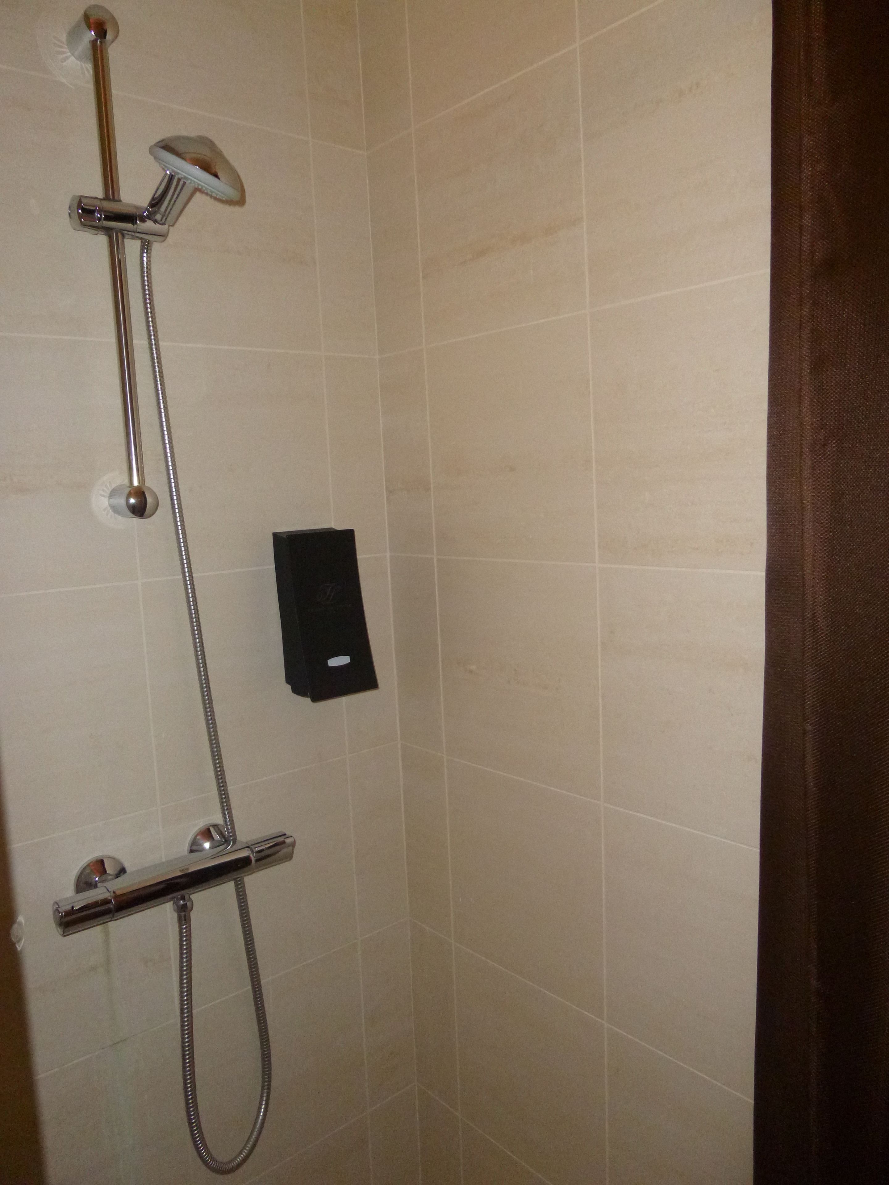 A shower with a handheld showerhead and a handheld faucet.