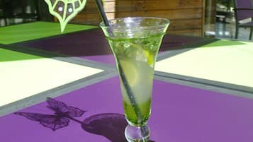 Ein Cocktailglas mit einer grünen Schmetterlingsdekoration auf einer violetten Tischdecke.