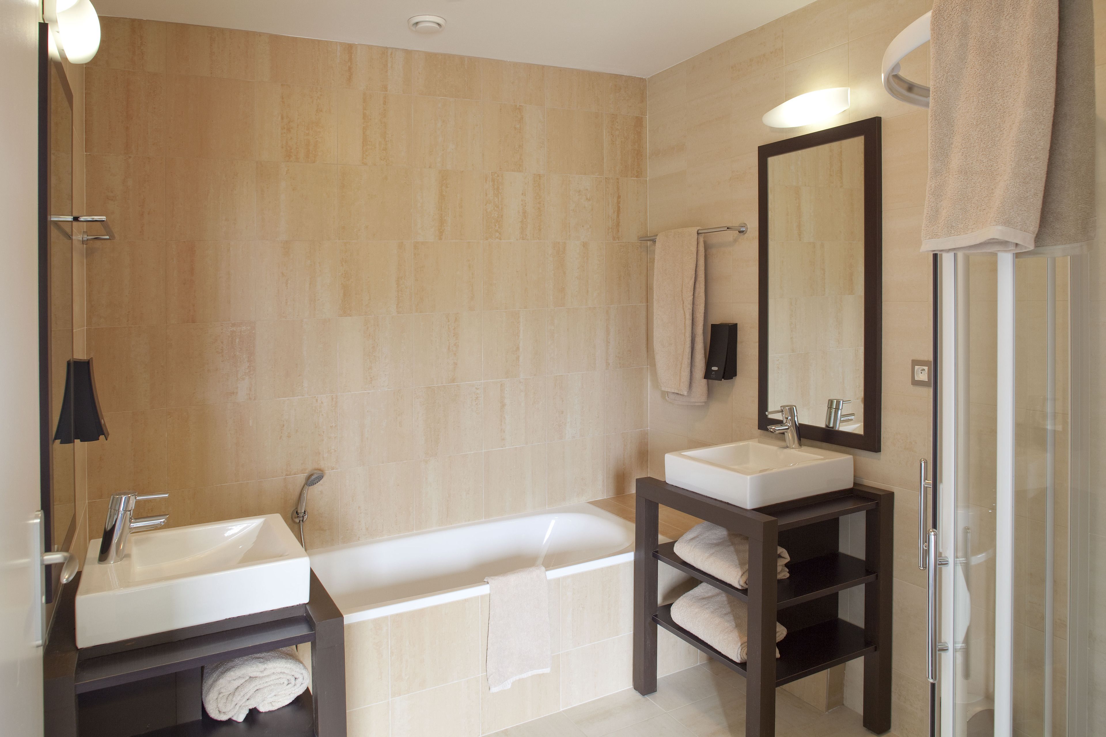 Un baño moderno con bañera, lavamanos, espejo y cabina de ducha de vidrio.