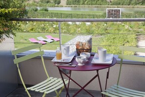 A balcony with a table set for breakfast, overlooking a green landscape.