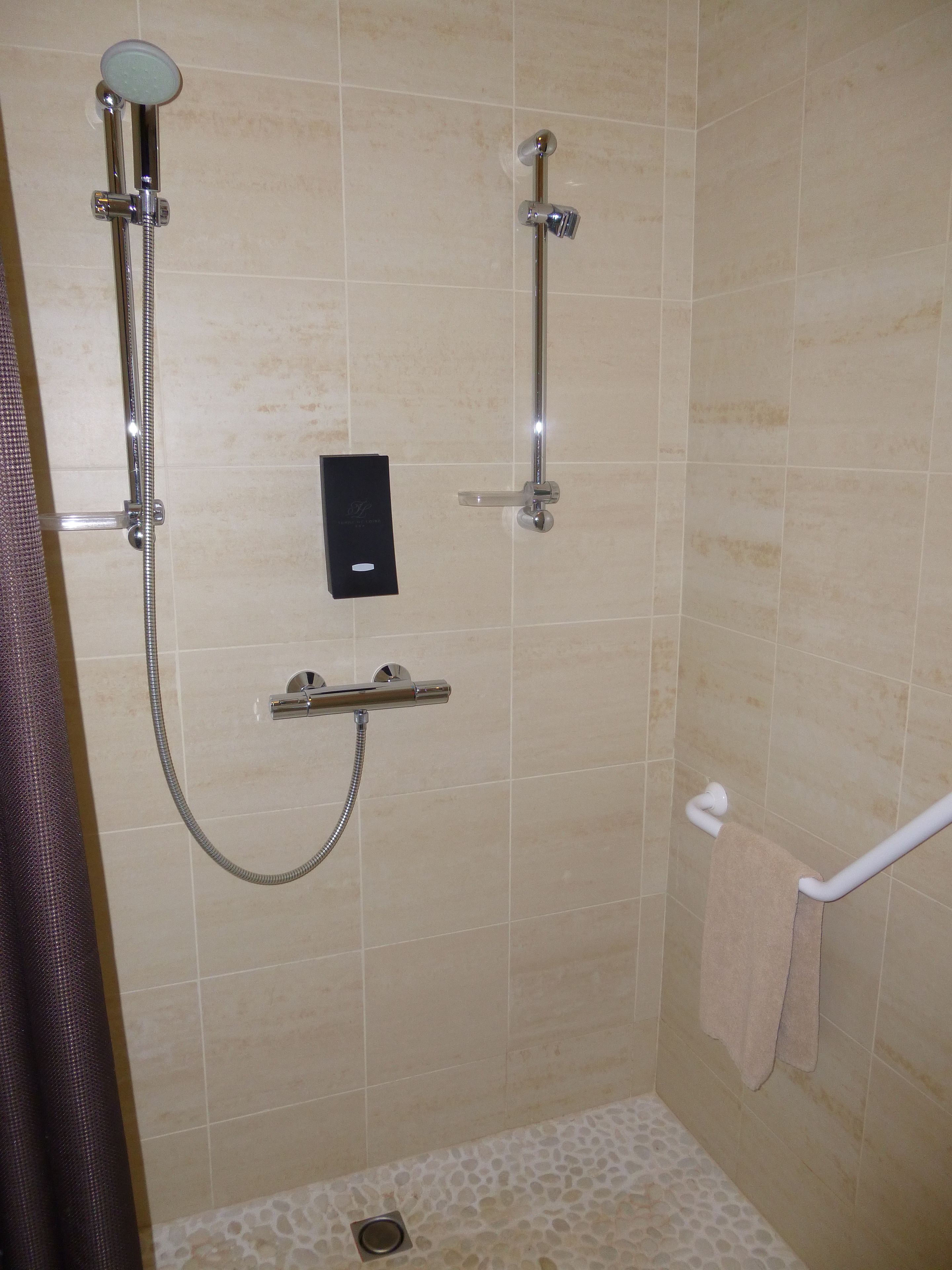 Una ducha con cabezal de ducha manual, rociador de mano y cabezal de ducha fijo en la pared.