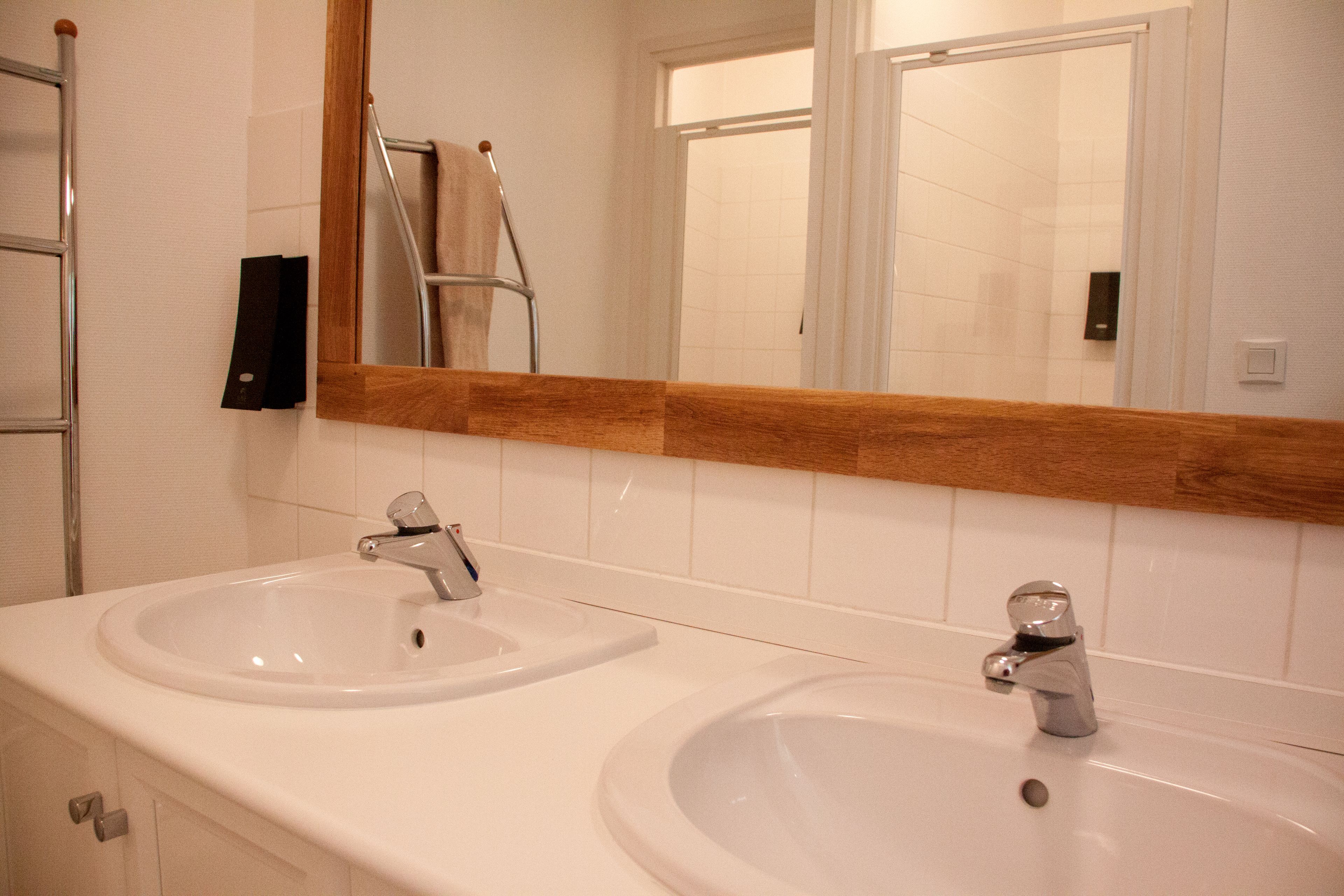 Een badkamer met twee wasbakken, een spiegel en een handdoekhouder.