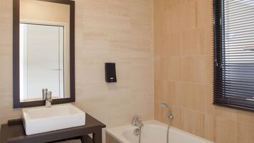 A bathroom with a white sink, a mirror, a bathtub, and a towel on the counter.