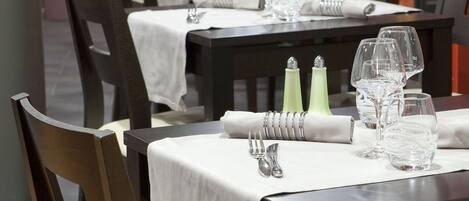 Un restaurant où les tables sont dressées, avec des chaises, et où l’aménagement est propre et bien organisé.
