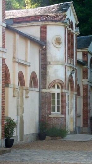 Um edifício com fachada de tijolos, janelas em arco e uma porta central.