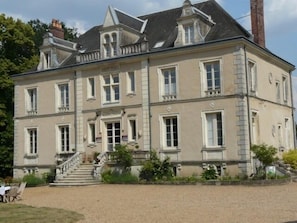 A large, two-story building with a symmetrical facade, multiple windows, and a central entrance with steps leading up to it.