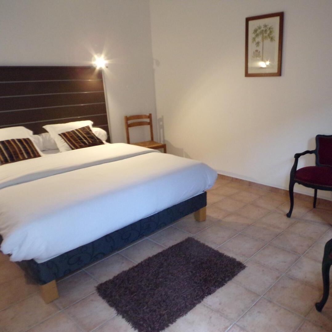 Un dormitorio con una cama doble, una mesita de noche, una silla, una lámpara y un cuadro en la pared.