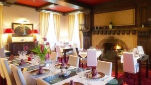 A dining area with tables set for a meal, a fireplace, and a painting on the wall. - Domaine de Bel Air (Cerans-Foulletourte)
