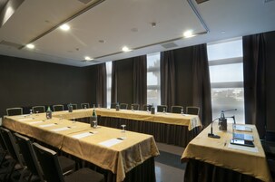 A conference room with long tables, chairs, and a laptop on one table.
