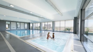 An indoor swimming pool with clear views of the cityscape through large windows.