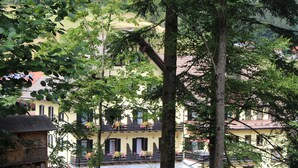 A building with balconies and flower boxes, surrounded by trees. - Hotel Adler - Post (Baiersbronn)